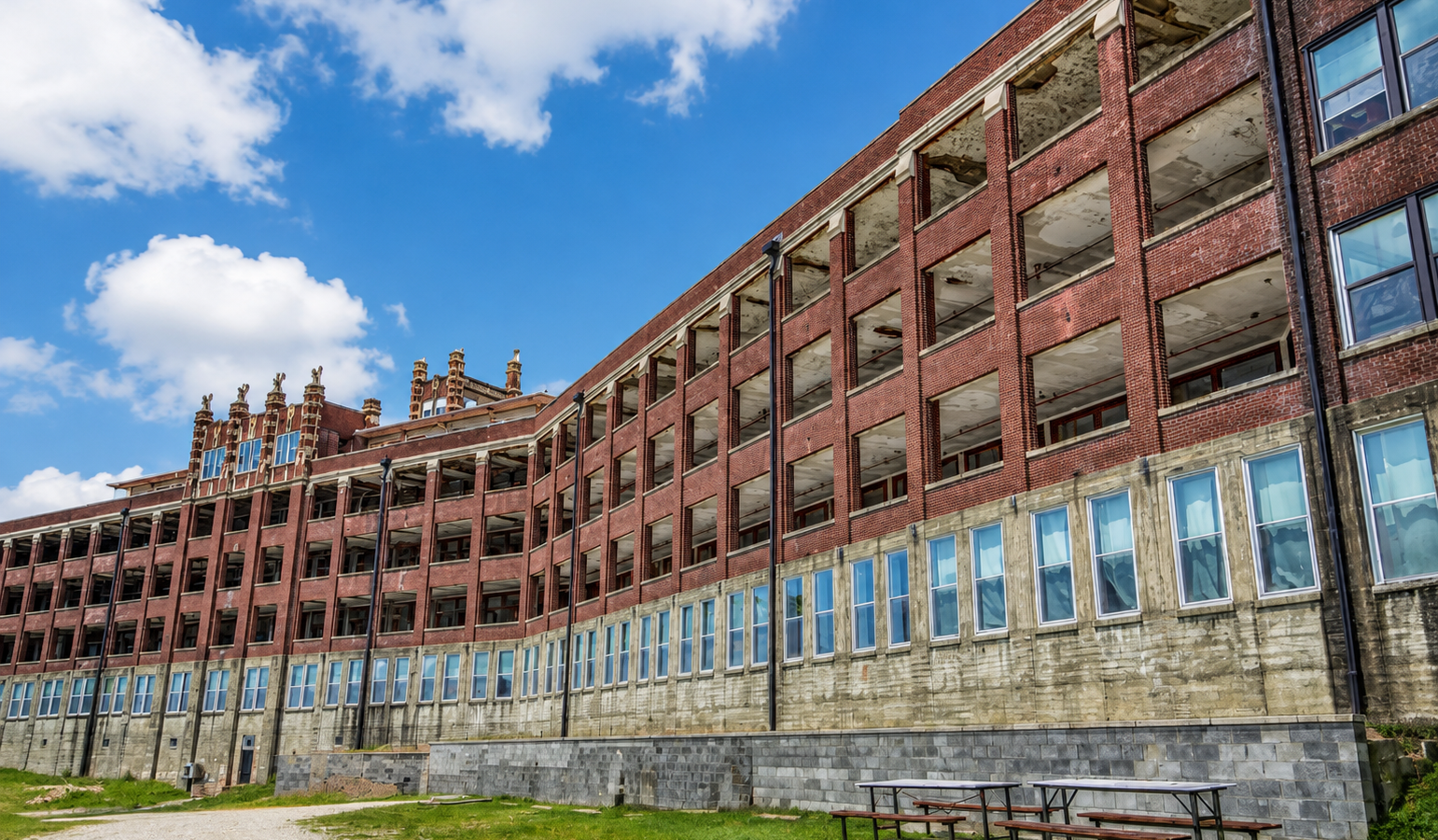 Abandoned historic red brick hospital building with dramatic cloudy sky during daytime